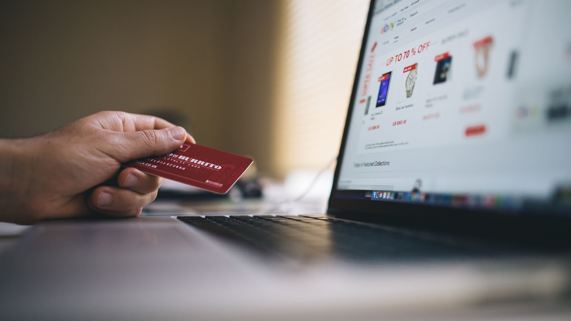 User with credit card browsing e-commerce website on laptop screen